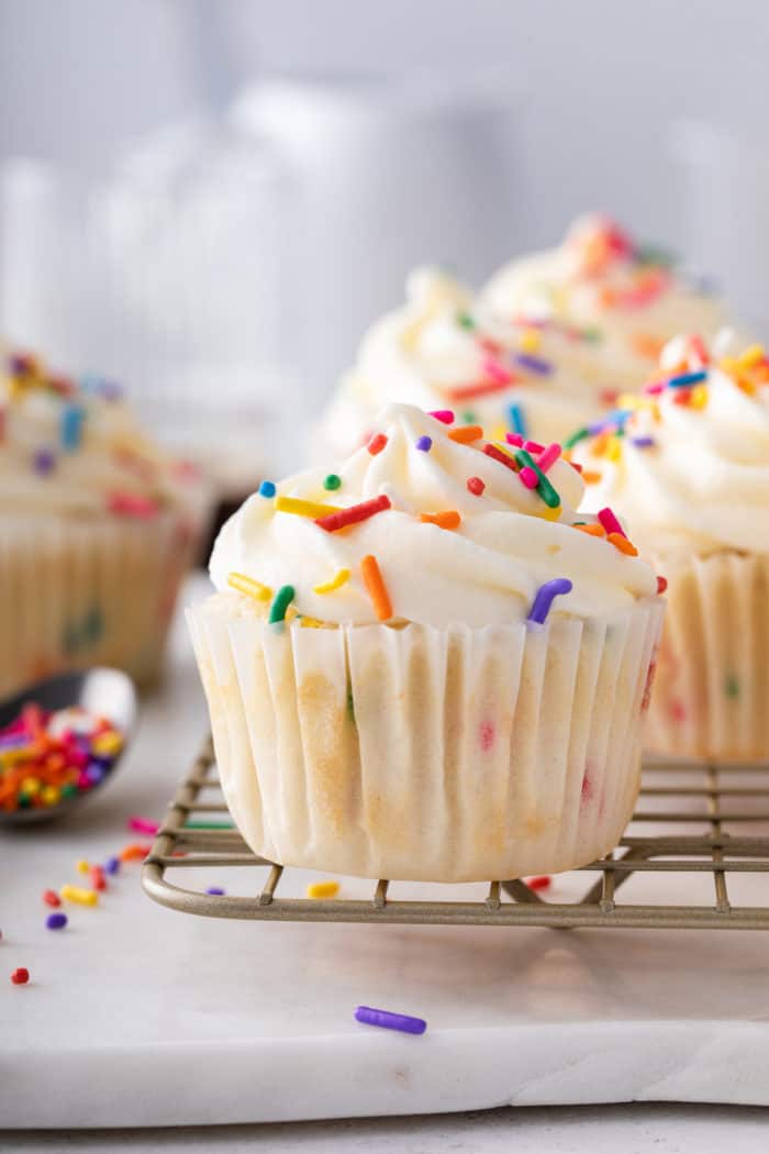 Close up of frosted funfetti cupcake on a wire cooling rack.