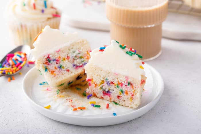 halved funfetti cupcake set on a white plate.