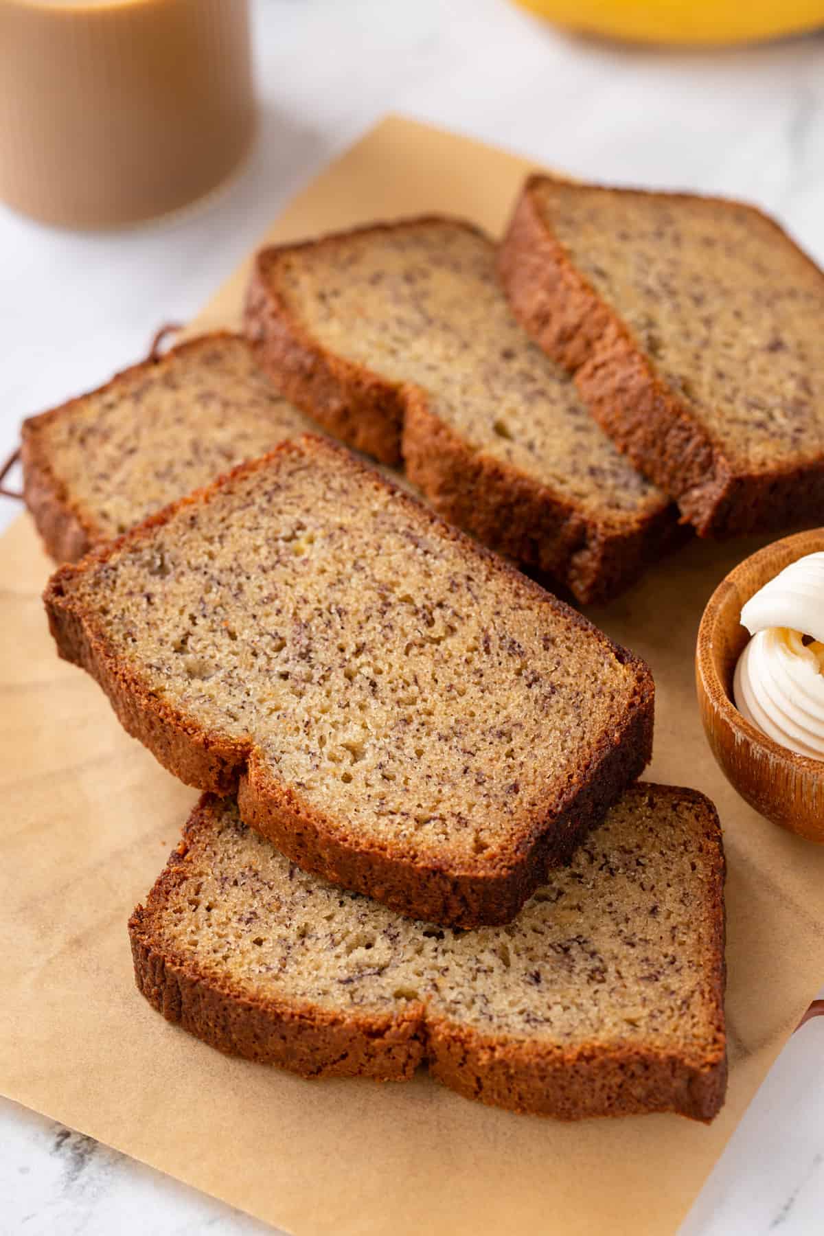 Several slices of dominique ansel's banana bread scattered on a piece of parchment paper.