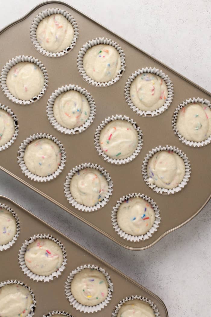 Unbaked funfetti cupcake batter in muffin tins, ready to be baked.