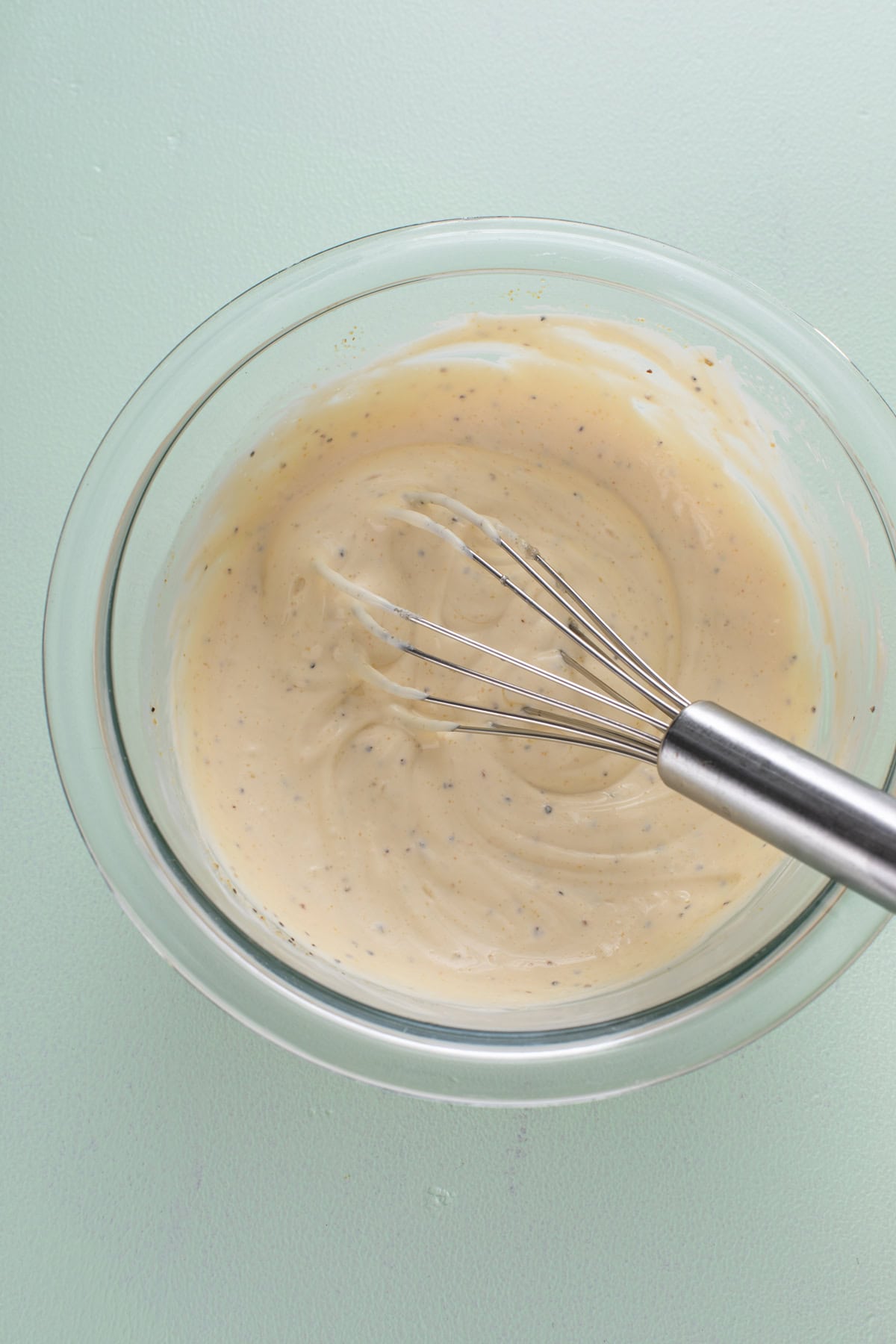 Base for blue cheese dressing whisked in a glass bowl.