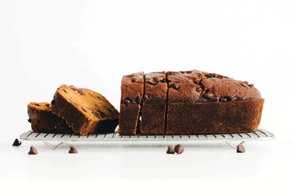 Side view of a sliced loaf of pumpkin chocolate chip bread on a cooling rack