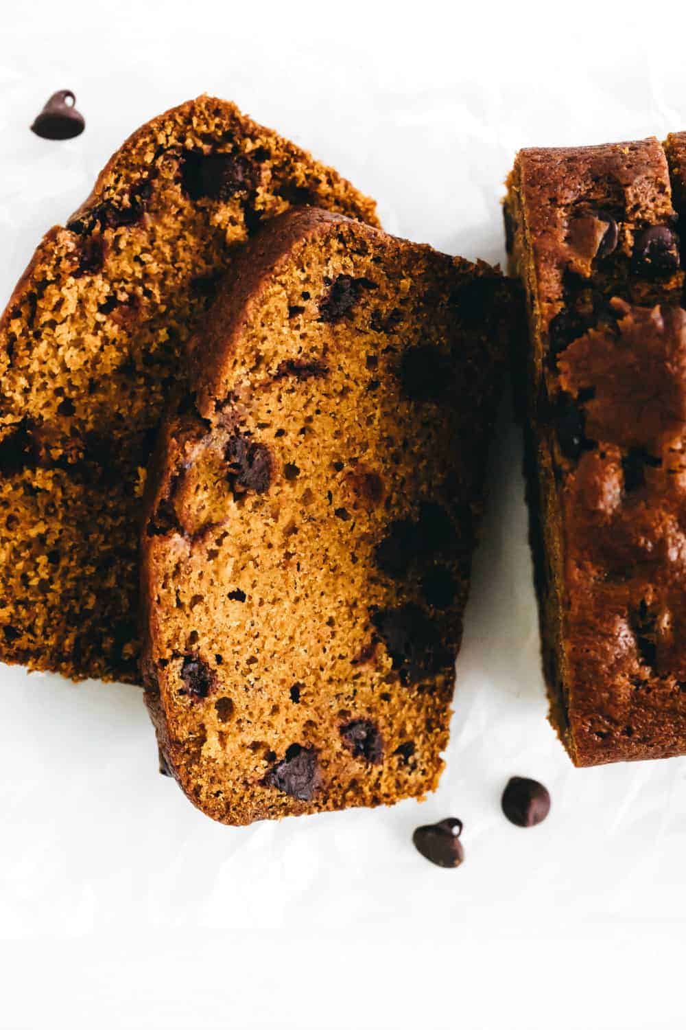 Sliced loaf of pumpkin chocolate chip bread on a light surface