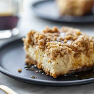 Slice of maple streusel cheesecake bar on a black plate