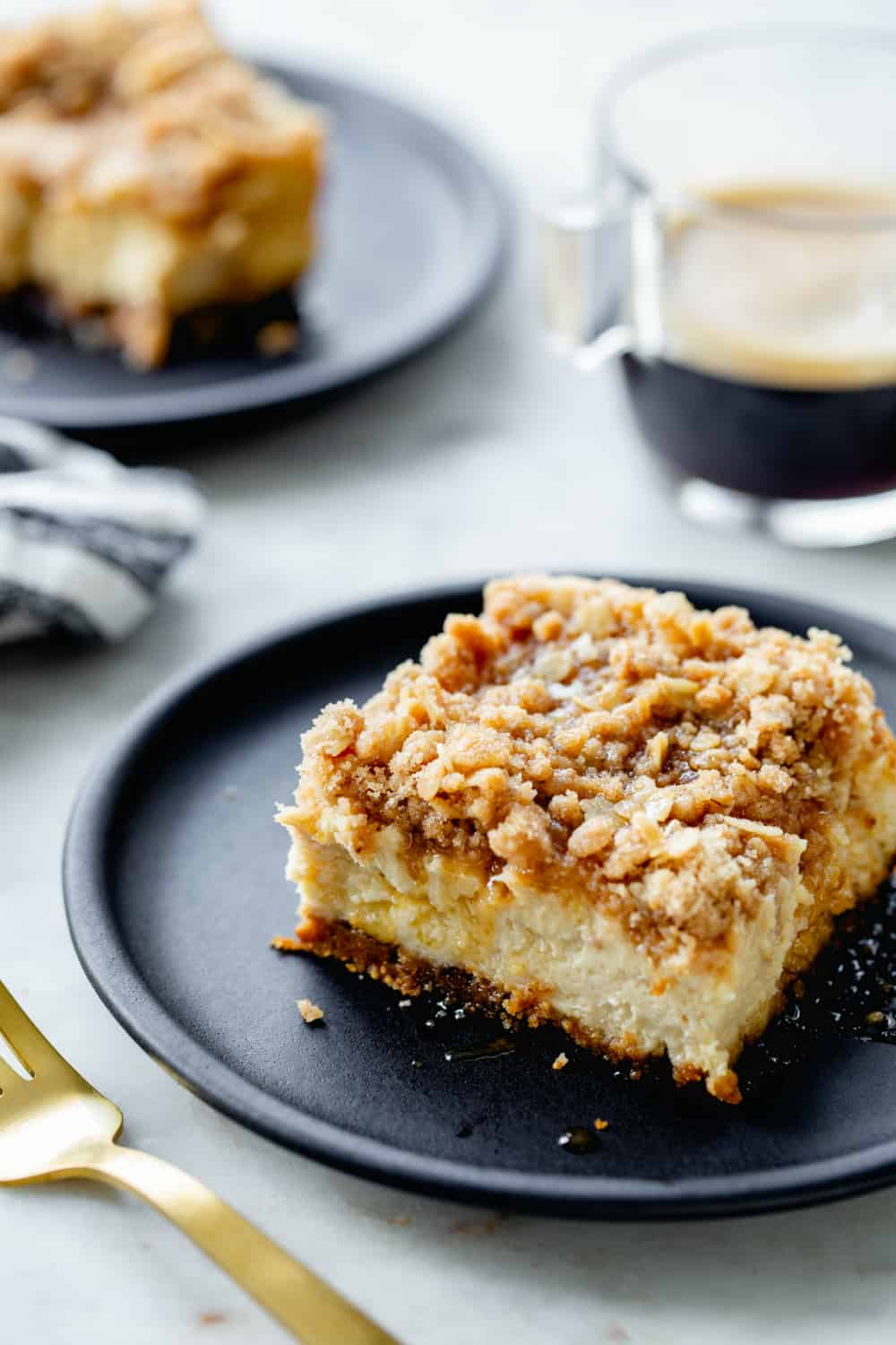 Plated maple cheesecake bars next to napkins and cup of espresso