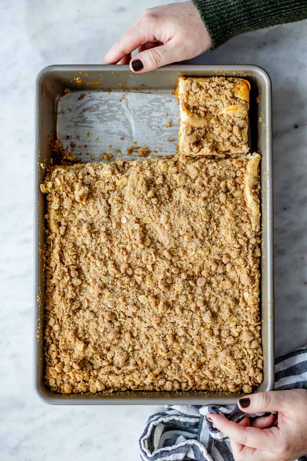 Pan of maple streusel cheesecake bars being placed on a marble countertop