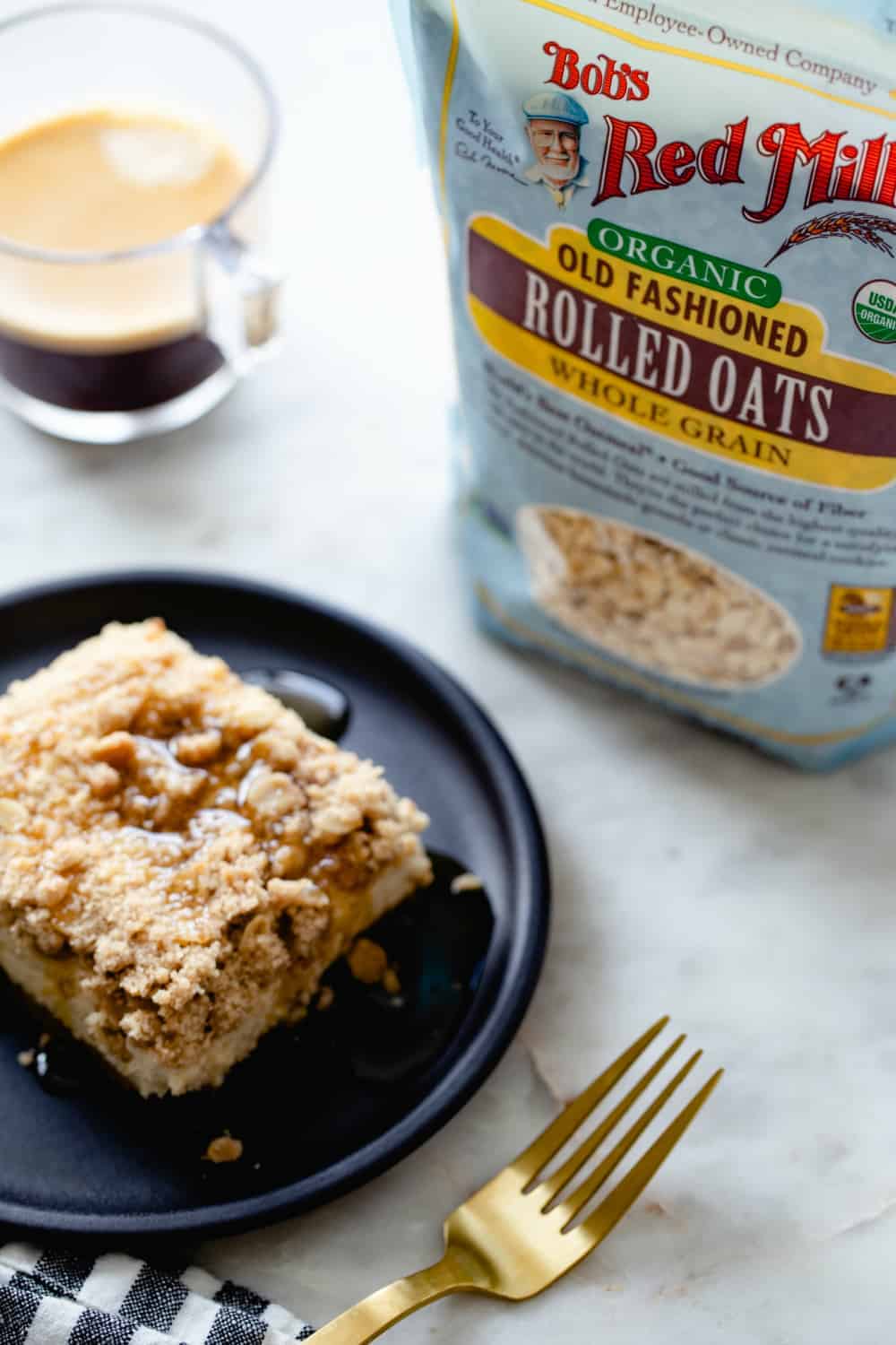 Bag of rolled oats behind a plate of maple streusel cheesecake bars