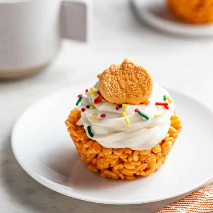 Pumpkin spice marshmallow treat cupcake on a white plate in front of a cup of coffee