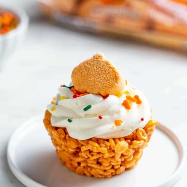 Plated marshmallow treat cupcake topped with a pumpkin spice marshmallow and sprinkles