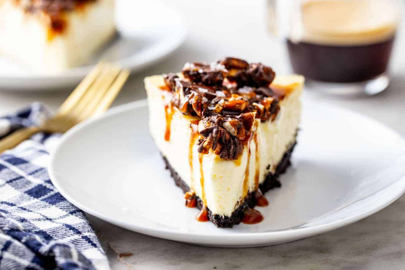 Slice of cheesecake topped with caramel sauce and chopped pretzels