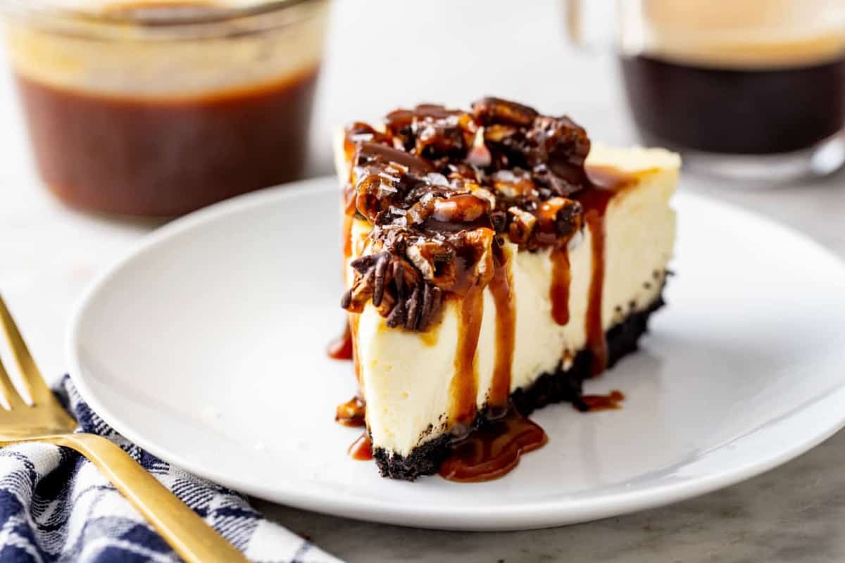 Slice of sweet and salty cheesecake in front of a jar of caramel and a cup of espresso