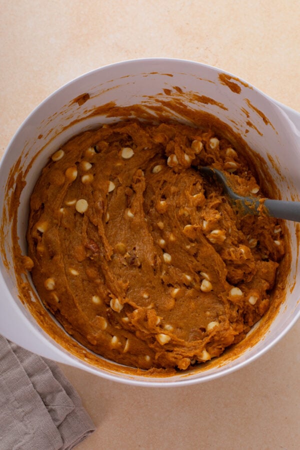 Batter for pumpkin blondies stirred in a white bowl.