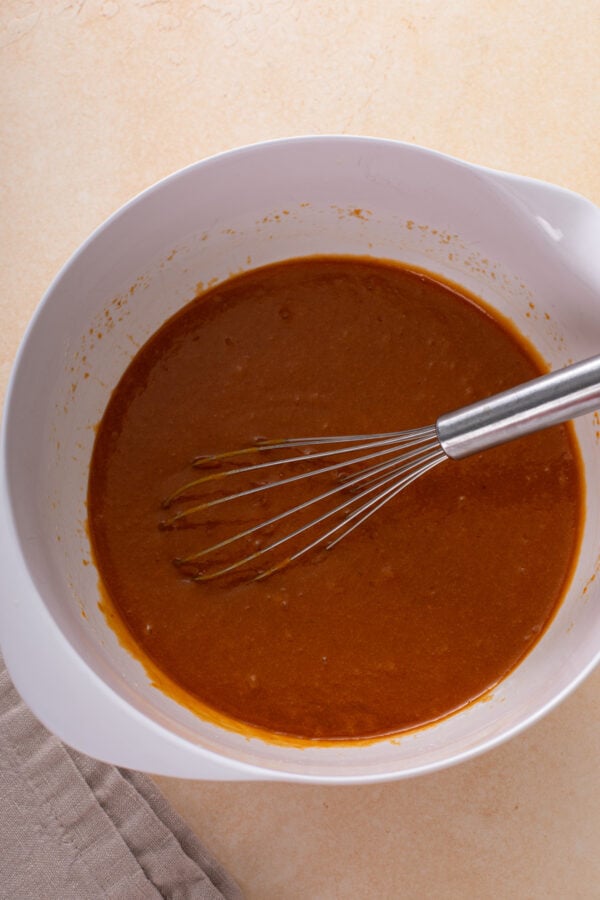 Wet ingredients for pumpkin blondies whisked in a white bowl.