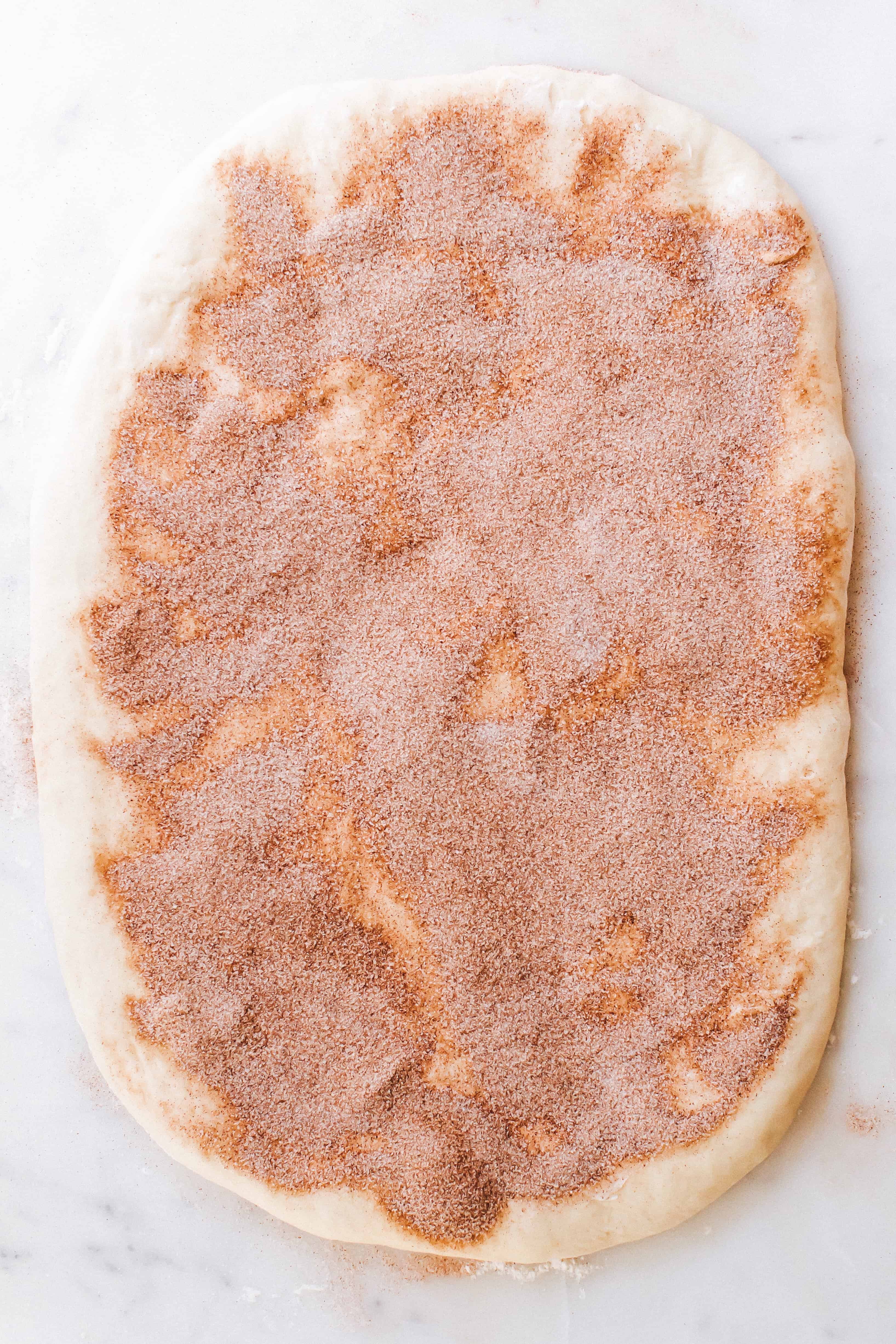 Cinnamon roll dough rolled out and topped with chai spiced filling