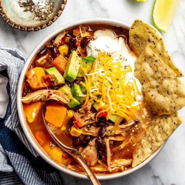 Bowl of tortilla soup made with rotisserie chicken. Garnished with tortilla chips, cheese and sour cream