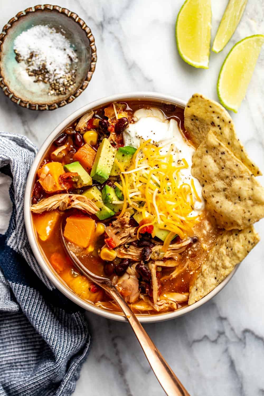 Bowl of tortilla soup made with rotisserie chicken. Garnished with tortilla chips, cheese and sour cream