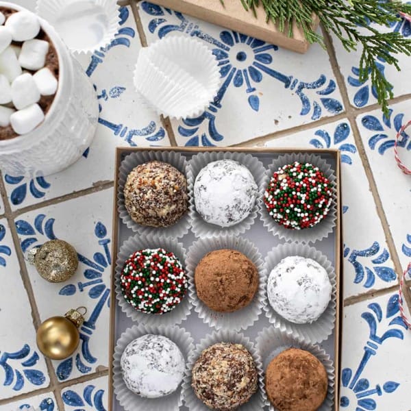 9 rum balls with assorted toppings arranged in a box for gifting
