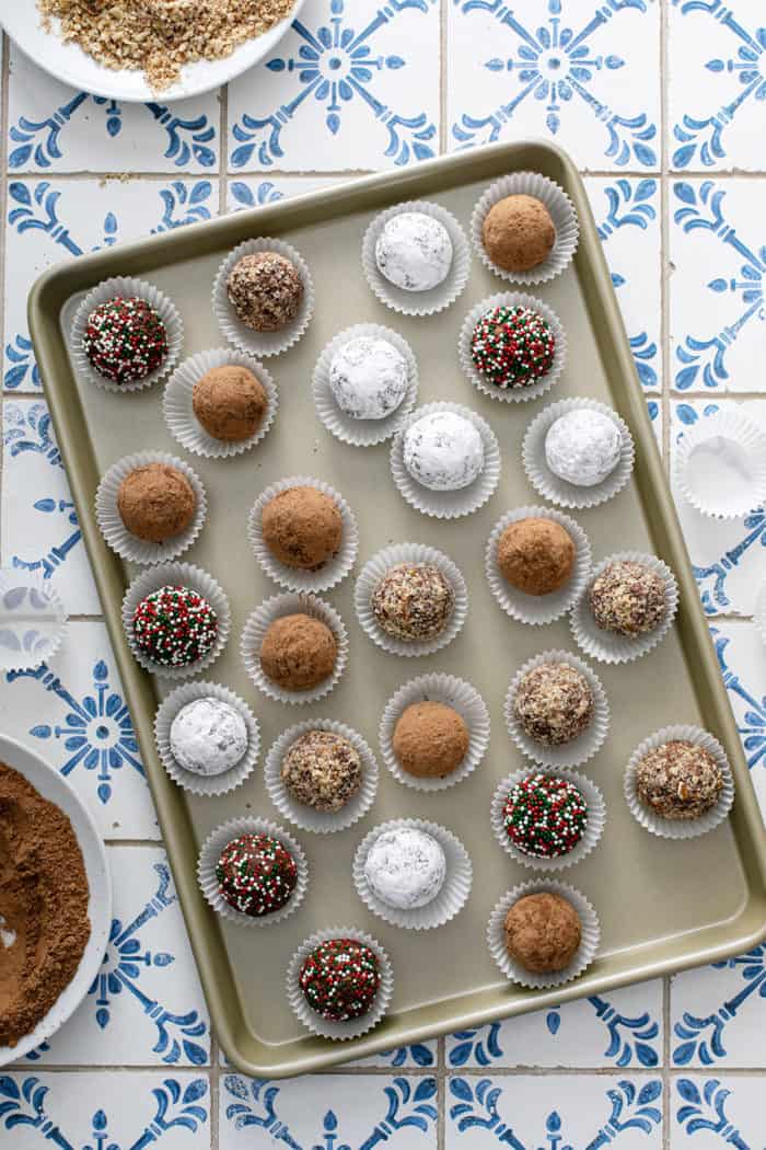 Overhead view of assorted rum balls in paper liners, arranged on a sheet tray
