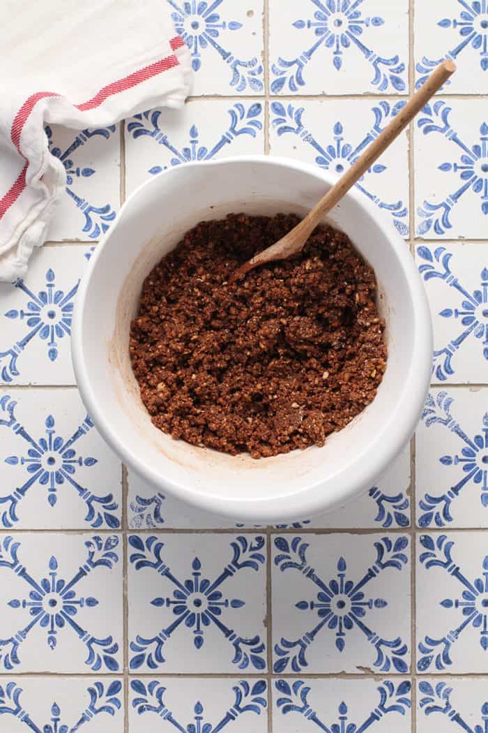 Rum ball dough being stirred together with a wooden spoon in a white bowl