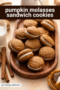 Delicious pumpkin molasses sandwich cookies with cream filling on a wooden tray.