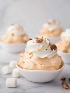 White bowls of pumpkin spice fluff garnished with whipped topping