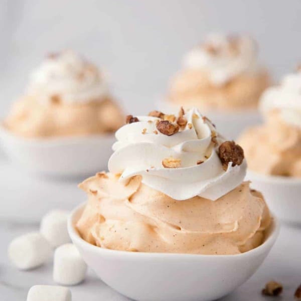 White bowls of pumpkin spice fluff garnished with whipped topping