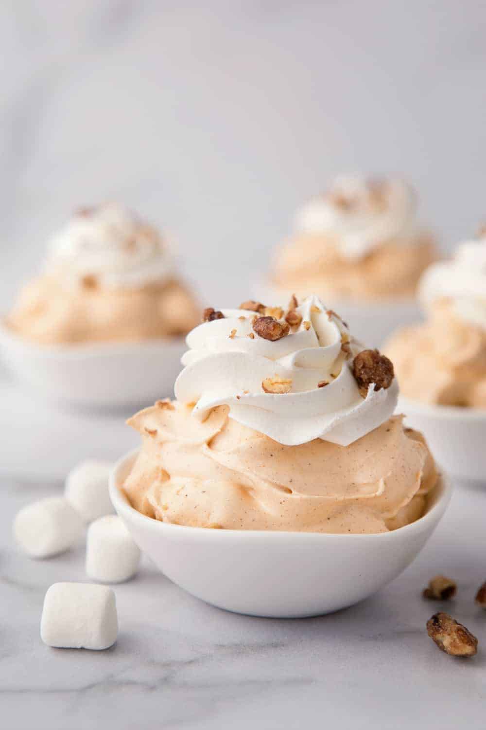 White bowls of pumpkin spice fluff garnished with whipped topping