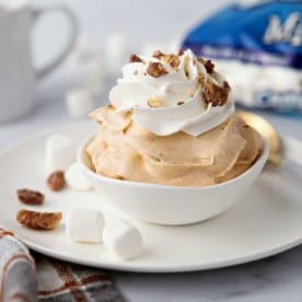 Bowl of pumpkin spice fluff with a cup of coffee and bag of mini marshmallows