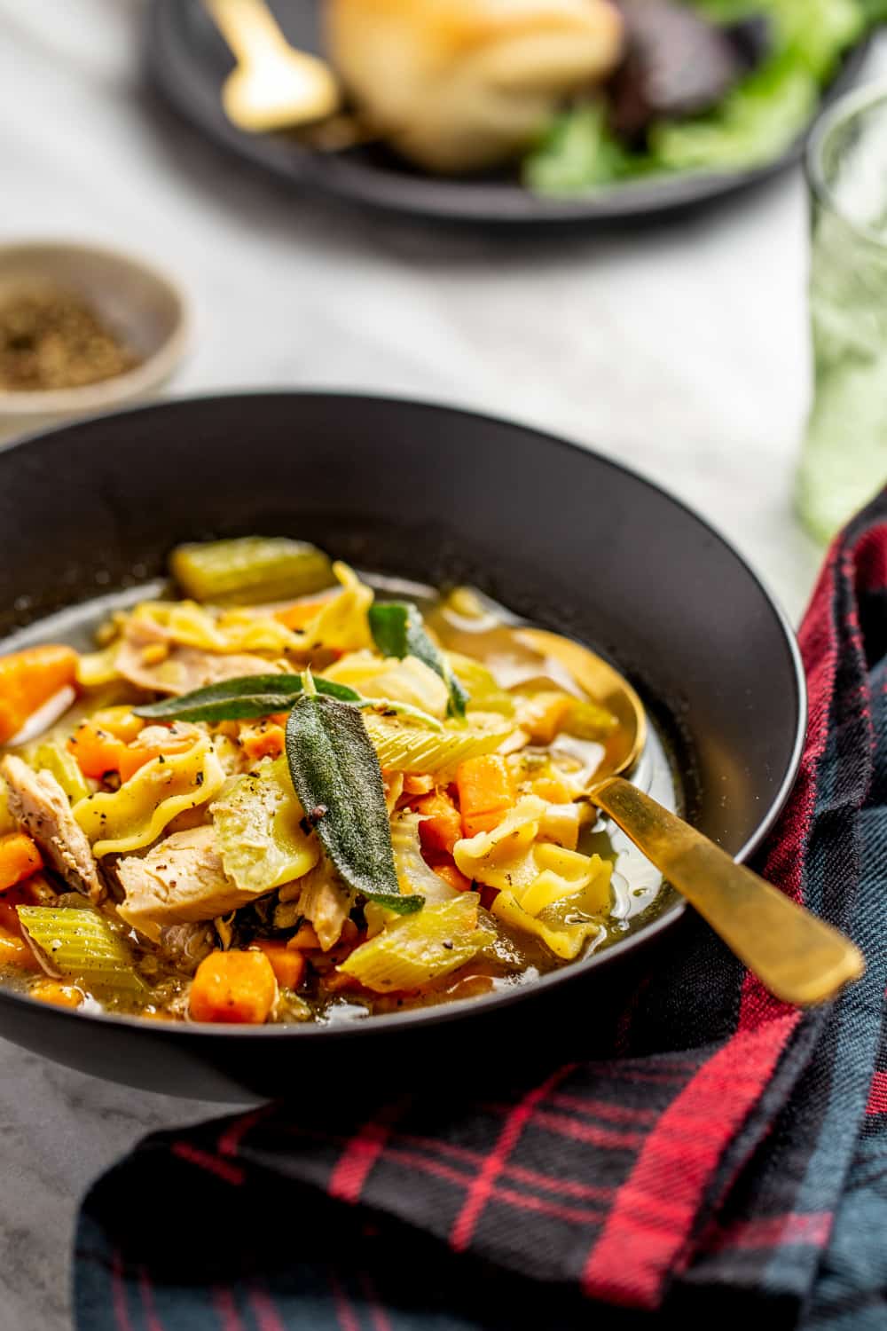 Close up of a bowl of turkey noodle soup with a gold spoon in the bowl