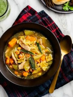 Easy turkey noodle soup made with leftover turkey in a black bowl by a gold spoon