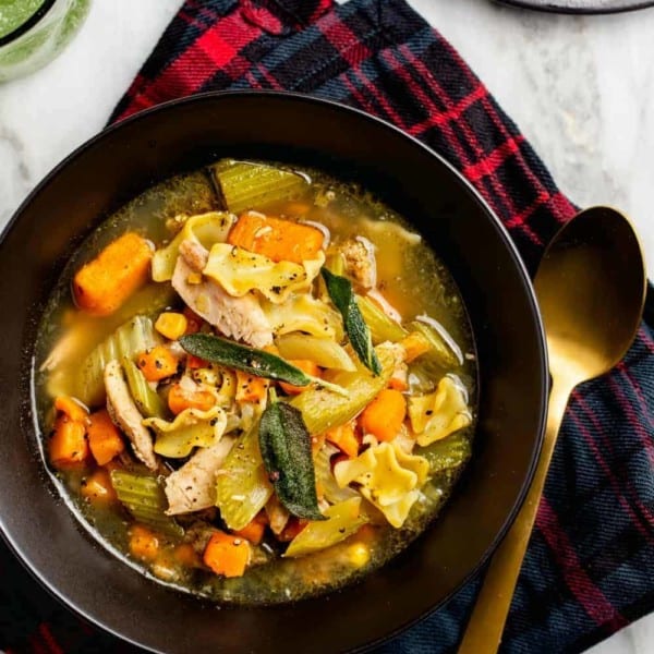 Easy turkey noodle soup made with leftover turkey in a black bowl by a gold spoon