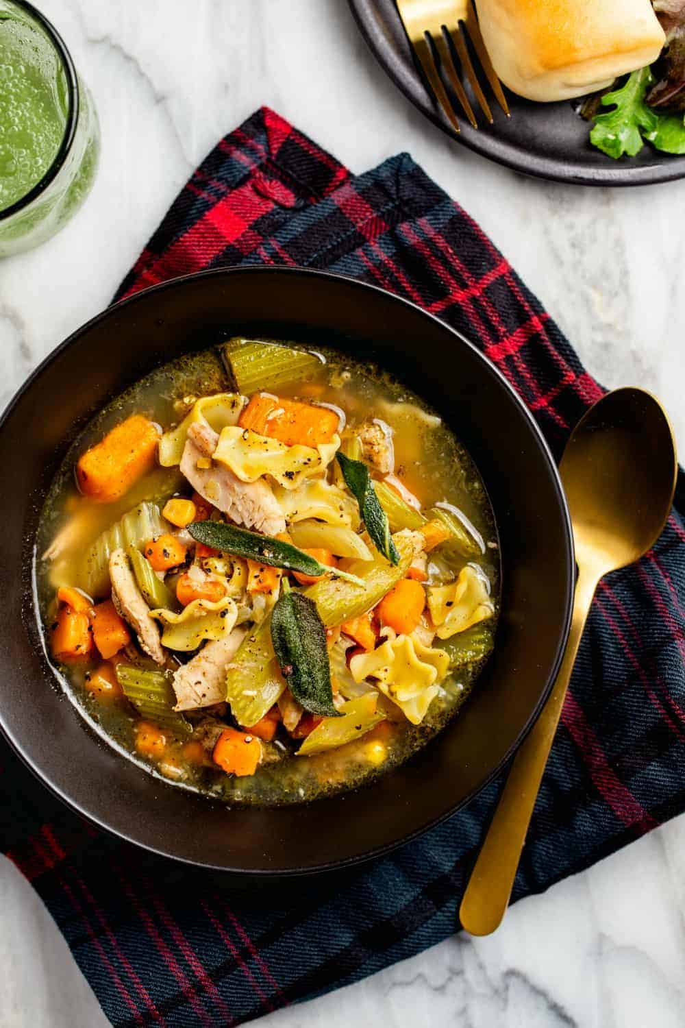 Easy turkey noodle soup made with leftover turkey in a black bowl by a gold spoon