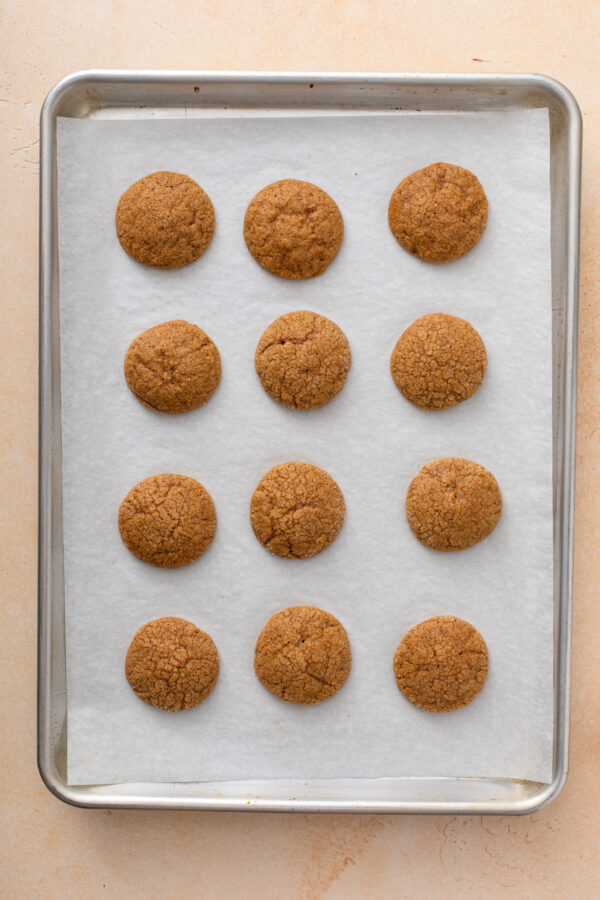 Baked pumpkin molasses cookies cooling on a parchment-lined baking sheet.