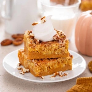 Close up image of two slices of pumpkin crunch cake stacked on a white plate.