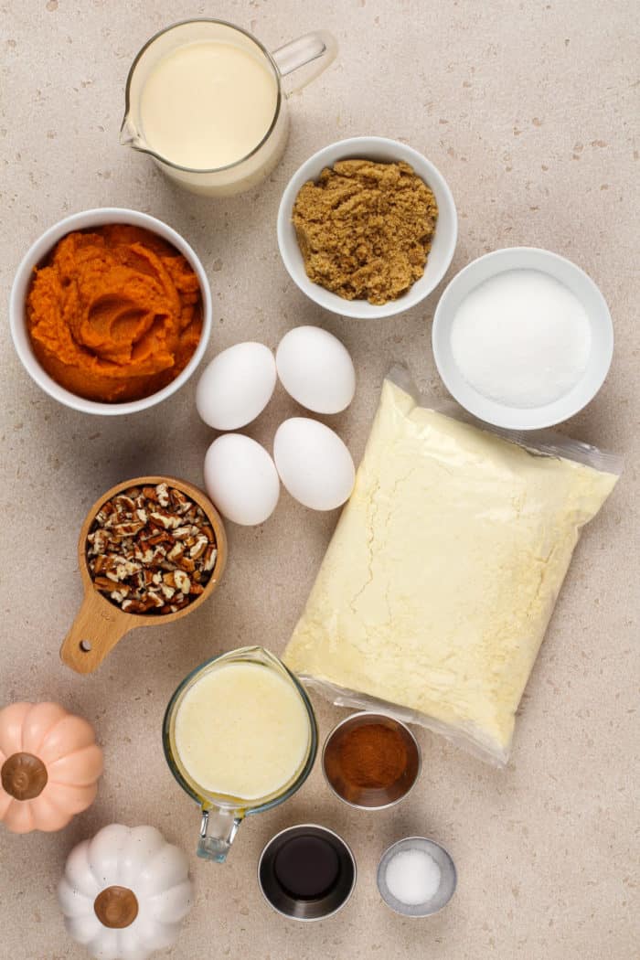 Pumpkin crunch cake ingredients arranged on a beige countertop.