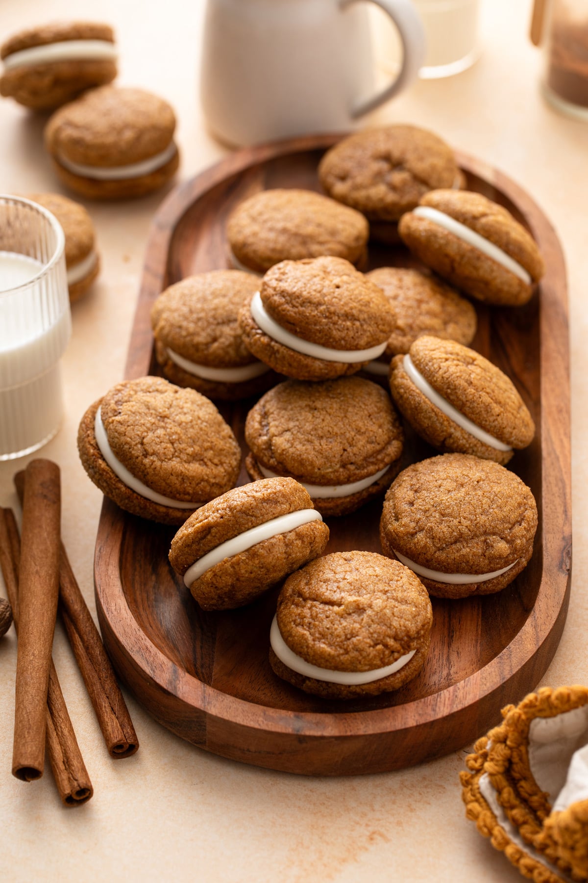 Batch of pumpkin molasses cookies arranged on a wooden platter next to a glass of milk.