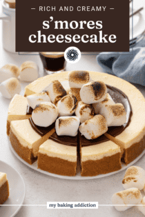 Sliced s'mores cheesecake topped with hot fudge sauce and toasted marshmallows. Text overlay includes recipe name.