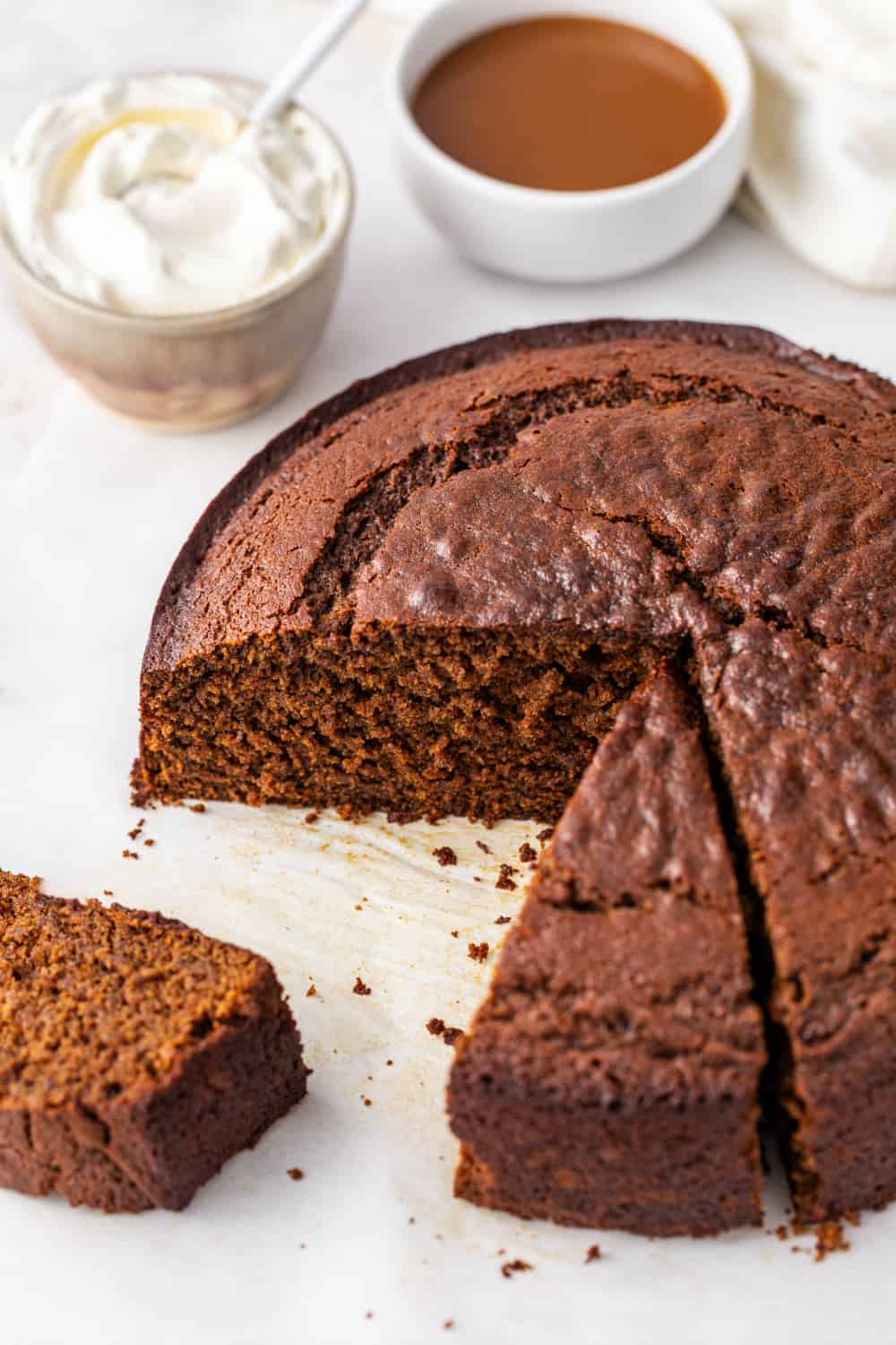 Gingerbread cake on a white surface with two slices cut out of it