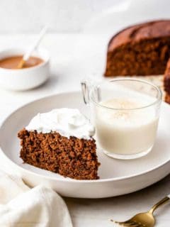 Slice of gingerbread cake and a glass of eggnog on a white plate