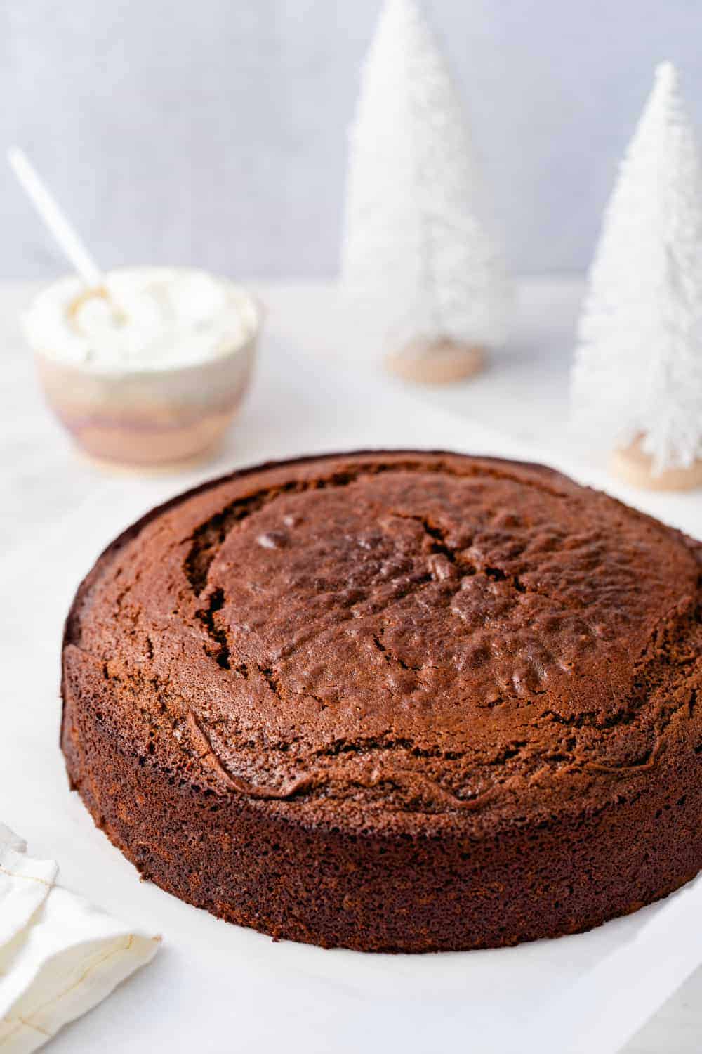 Gingerbread cake on a marble surface with a bowl of whipped cream in the background
