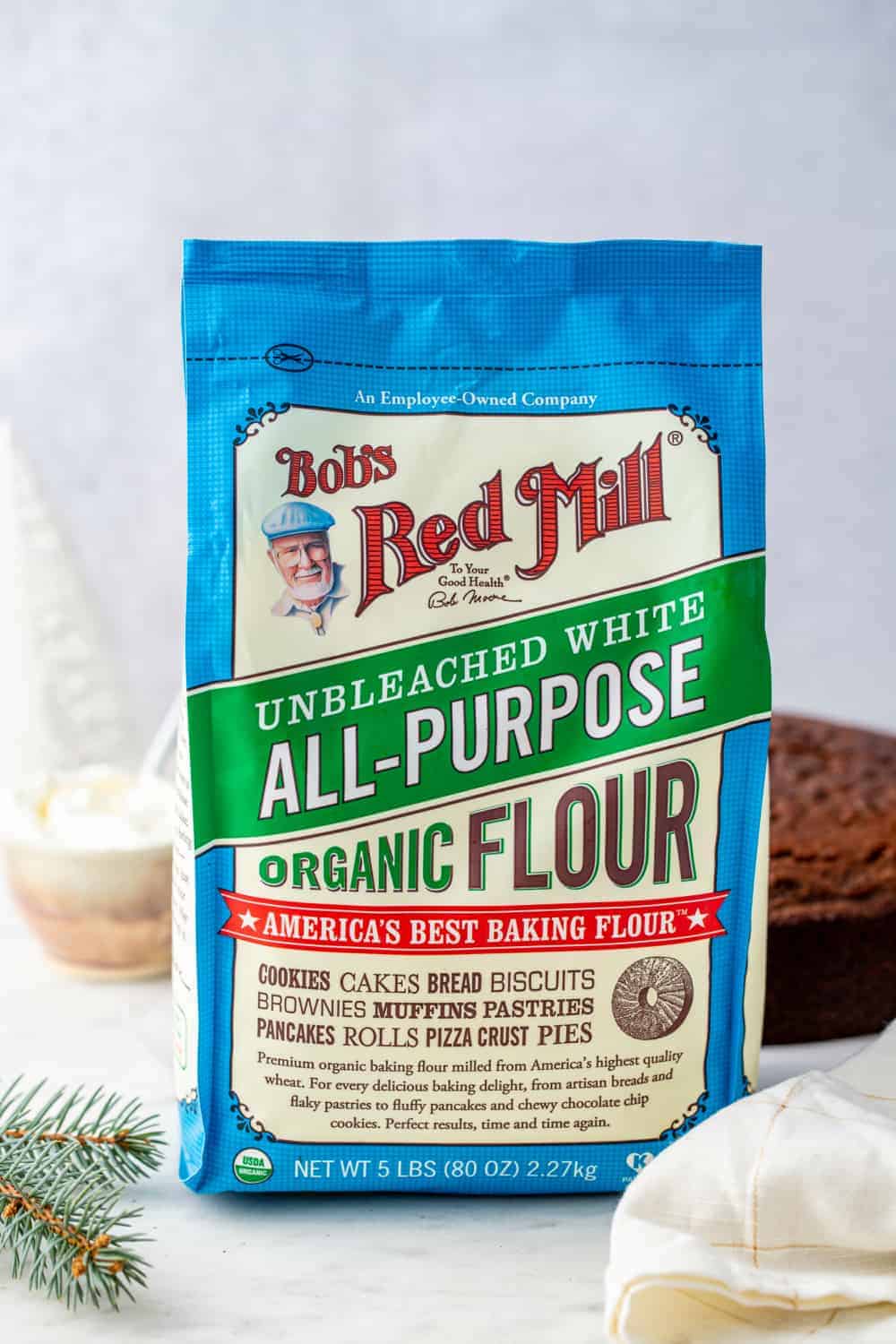 Bag of all-purpose flour in the foreground with gingerbread cake in the background