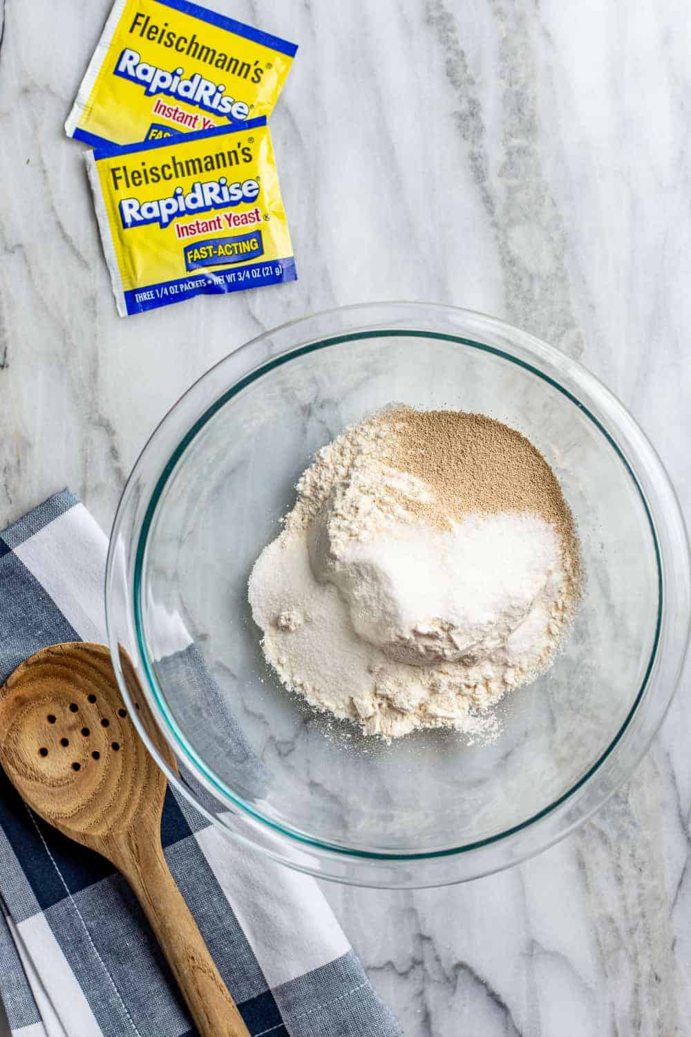 Dry ingredients for 30 minute pizza crust in a glass mixing bowl on a marble surface