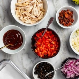 Assorted toppings and sauces for a DIY pizza bar in small bowls