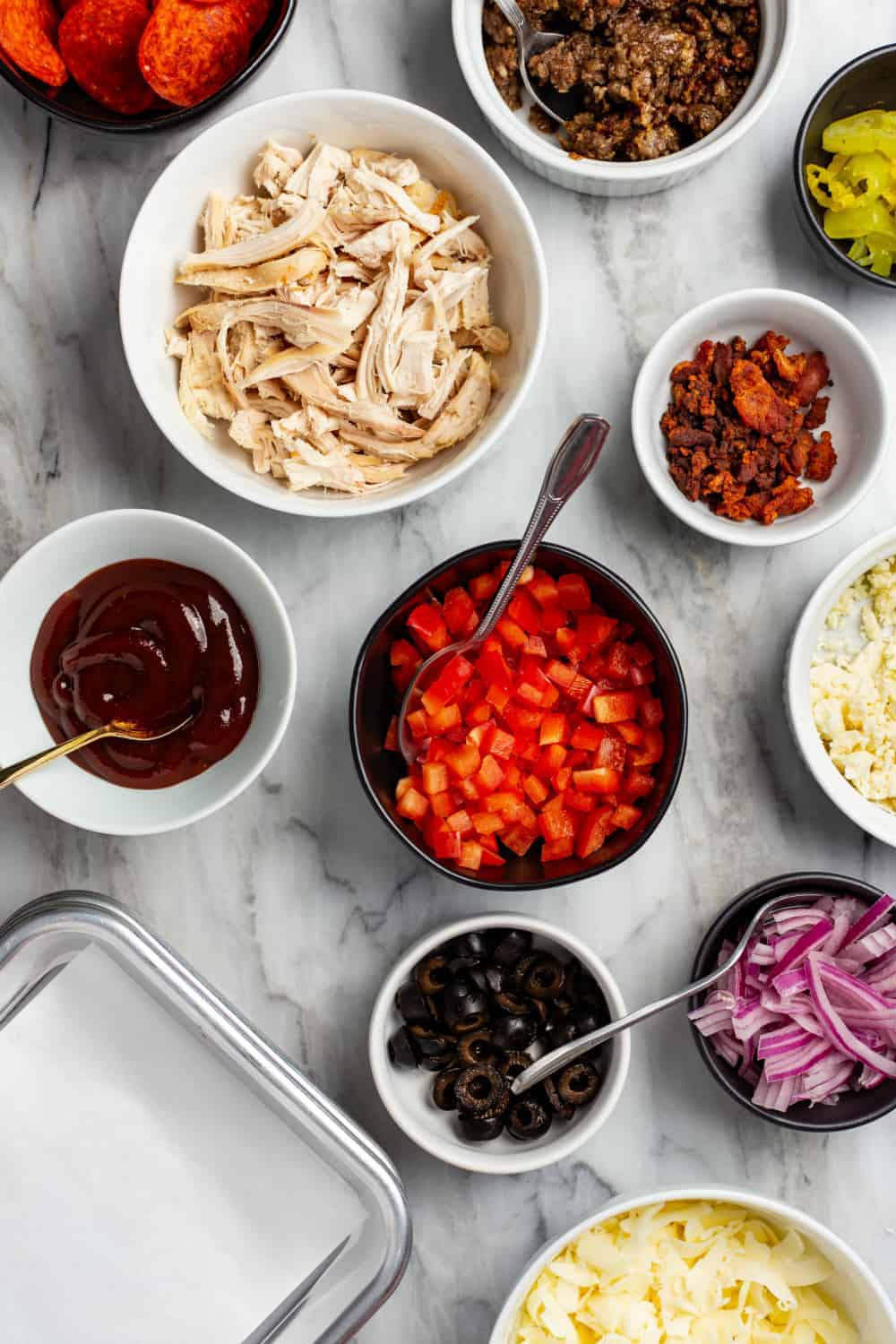 Assorted toppings and sauces for a DIY pizza bar in small bowls