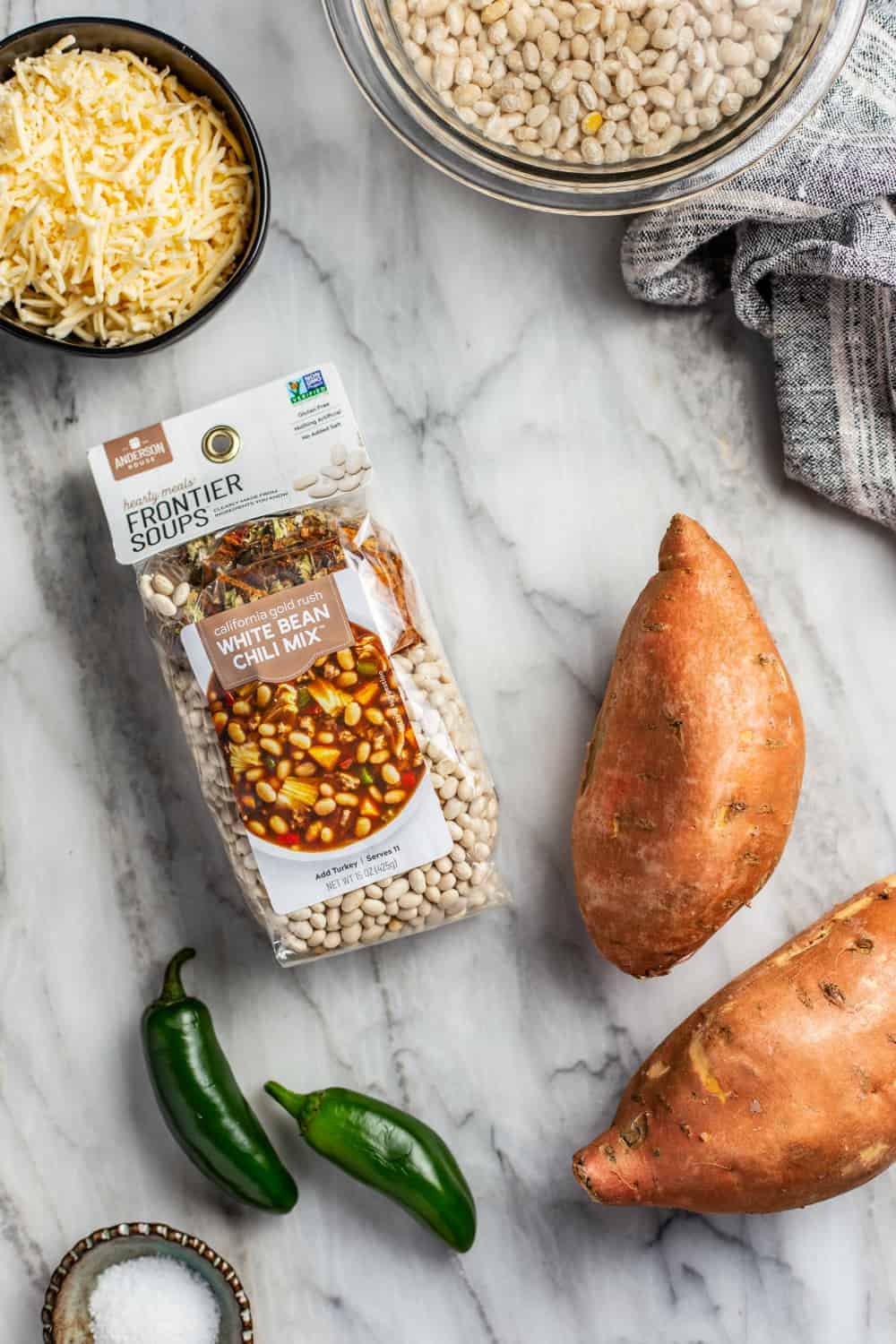 Ingredients for white bean chicken chili on a marble countertop