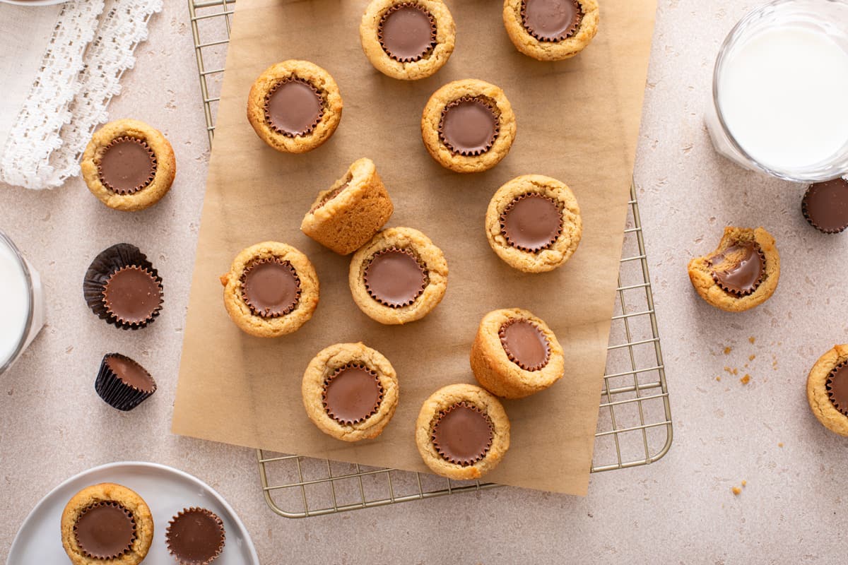 Overhead view of peanut butter cup cookies arranged on a wire rack next to a glass of milk.