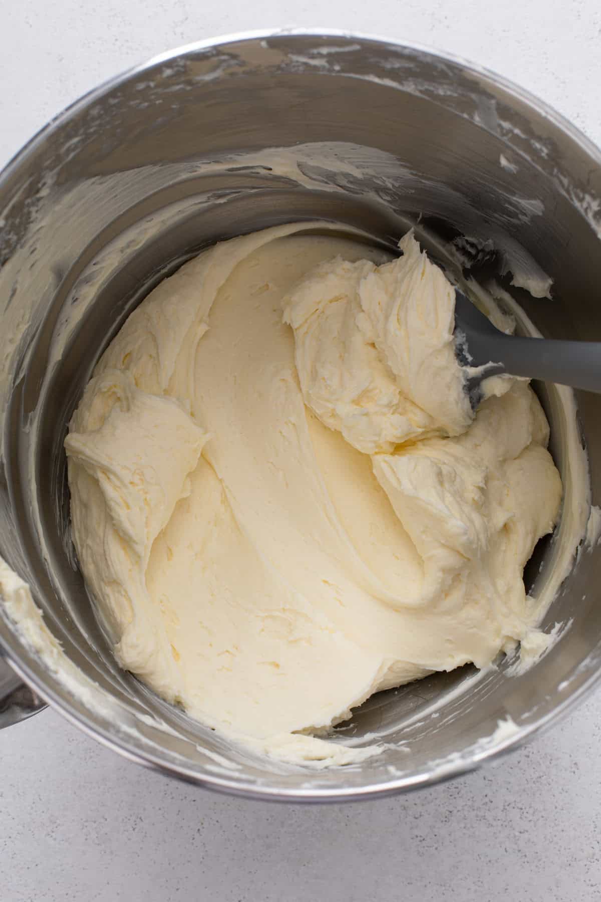 Cream cheese beaten with sugar in a mixing bowl.