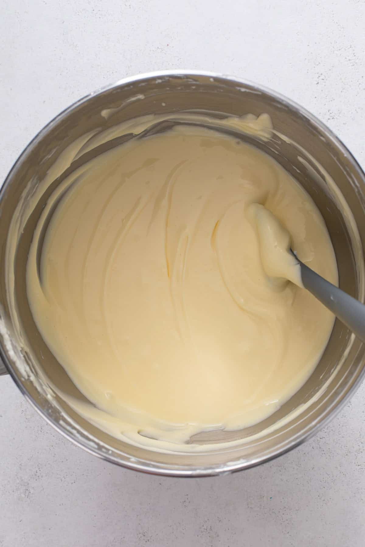 Cream cheese, sugar, and eggs mixed in the bowl of a stand mixer.