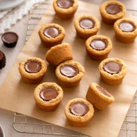 Peanut butter cup cookies scattered on a piece of parchment paper over a wire rack.