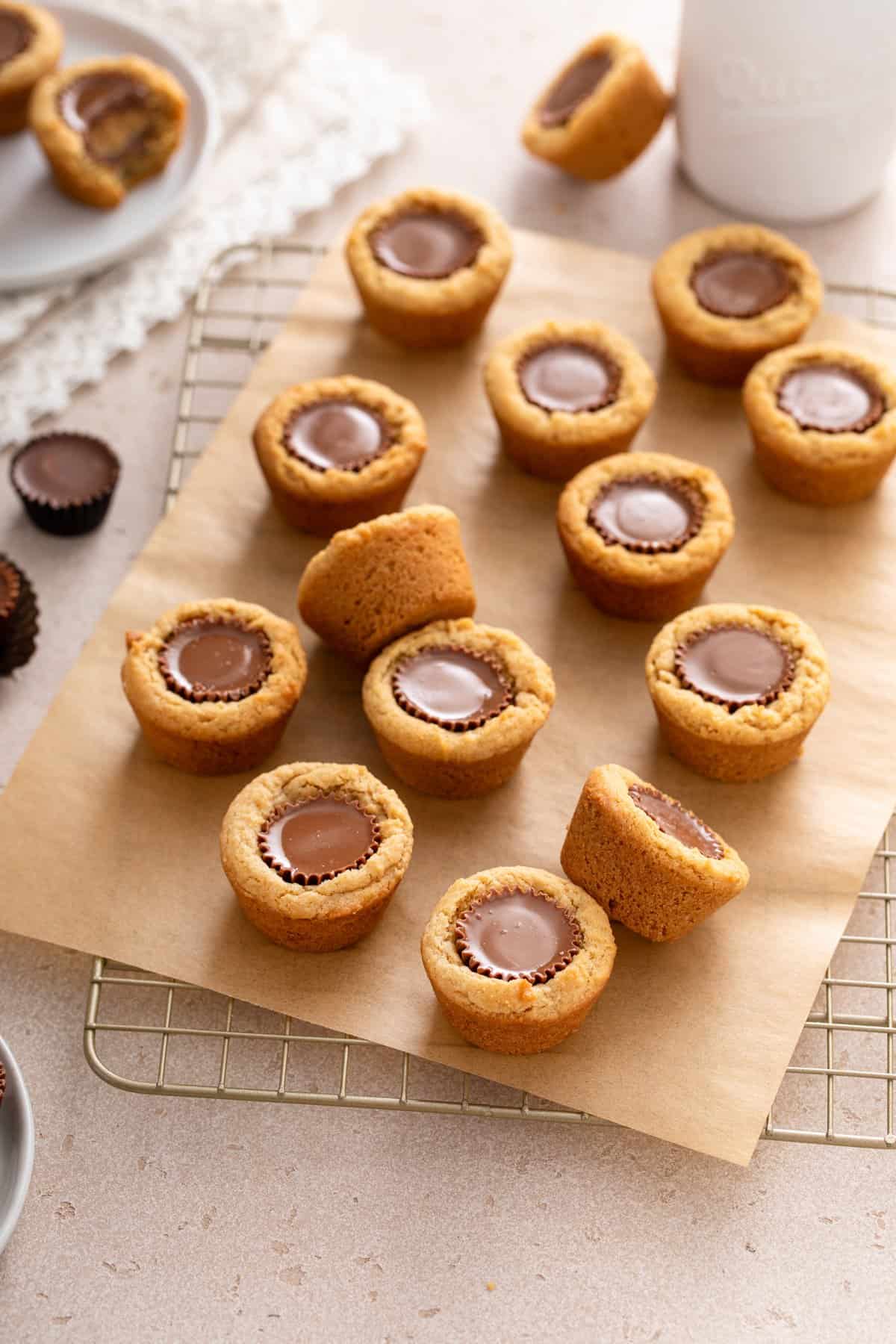Peanut butter cup cookies arranged on a piece of parchment paper on top of a wire cooling rack.